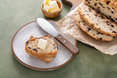 Soda bread in a cast iron pan with cranberries and pecans sliced and served with irish butter, irish recipe idea with St Patricks day