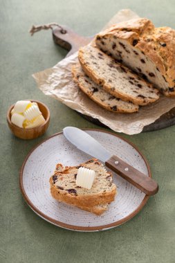 Soda bread in a cast iron pan with cranberries and pecans sliced and served with irish butter, irish recipe idea with St Patricks day