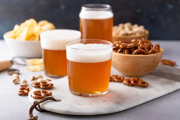 テーブル上のさまざまなスナックとメガネの伝統的なラガービール — ストック写真