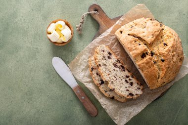 Soda bread in a cast iron pan with cranberries and pecans sliced and served with irish butter, irish recipe idea with St Patricks day