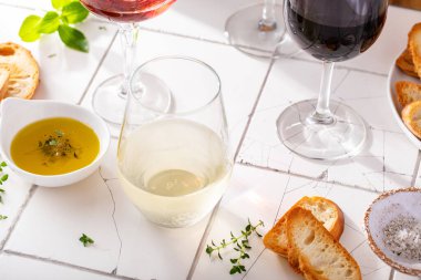 Farklı bardaklarda zeytin yağı ve güneş ışığında baget ile servis edilen çeşitli üzümler.