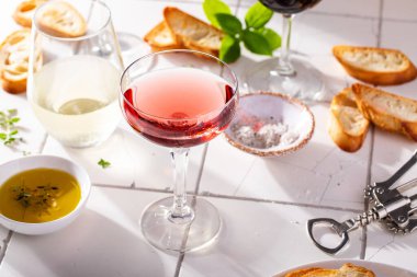 Farklı bardaklarda zeytin yağı ve güneş ışığında baget ile servis edilen çeşitli üzümler.