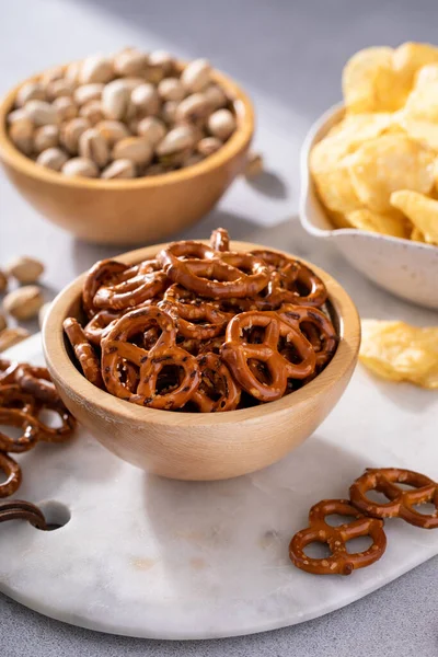 stock image Variety of salty snacks on the table with pretzels, pistachios and potato chips, snacks that go well with beer