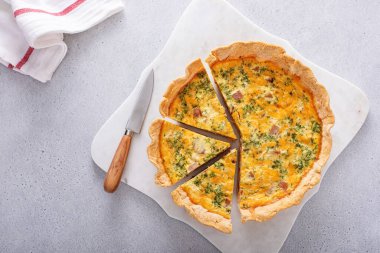 Ev yapımı jambonlu kiş, çedar peyniri ve maydanoz. Masanın üstünde fotokopi alanı ile kesilmiş.