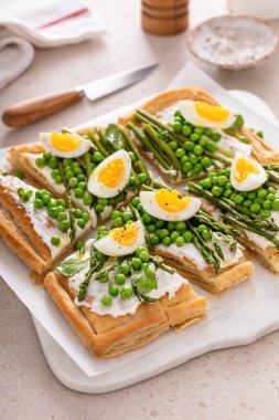 Taze bahar turtası, yeşil bezelye, haşlanmış yumurta ve kuşkonmaz. Parçalara ayrılmış börek.