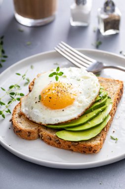 Tam tahıllı avokado tostu, üstüne sahanda yumurta, sağlıklı kahvaltı fikri.