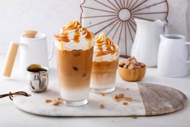 Büyük bardakta buzlu karamel latte. Karamel sosu damlaları, süslü kahve içeceği.