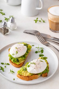 Avokado püresiyle ekşi tost ve haşlanmış otlu yumurta, sağlıklı kahvaltı fikri.