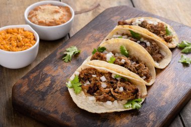 Kesme tahtasında soğan ve kişniş soslu domuz carnitas taco