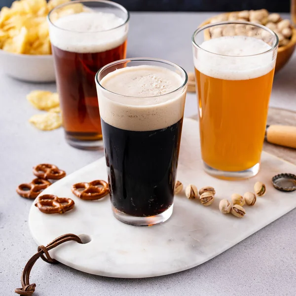 ダークスタウト 伝統的なラガーとベルギーの白のビールのバリエーションは コピースペースとテーブル上のスナックを提供 — ストック写真