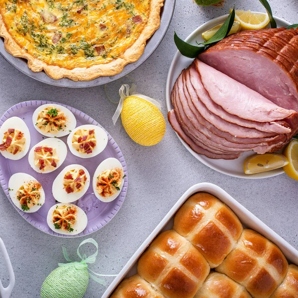 Easter brunch table with ham, quiche, hot cross buns and deviled eggs top view