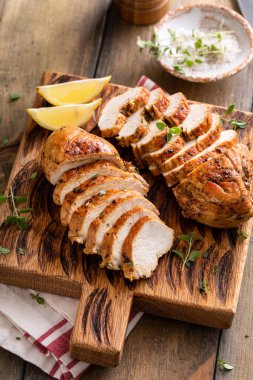 Izgara ya da kızarmış tavuk göğsü, bütün ve ahşap servis tabağında dilimlenmiş.