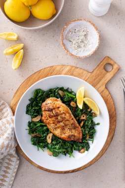 Kızarmış tavuk sotelenmiş ıspanak ve limon, sağlıklı akşam yemeği fikri.