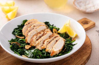 Kızarmış tavuk sotelenmiş ıspanak ve limon, sağlıklı akşam yemeği fikri.