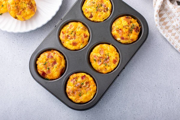 Breakfast egg muffins or egg bites with potato, bacon and cheddar in a muffin tin