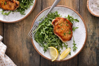 Sarımsakla pişirilmiş domuz pirzolası ve tabakta roka salatası.