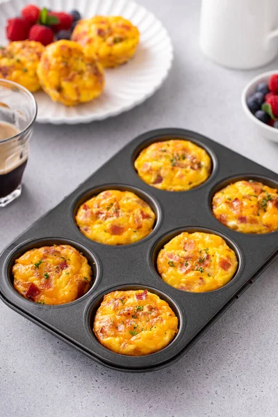 Breakfast egg muffins or egg bites with potato, bacon and cheddar in a muffin tin