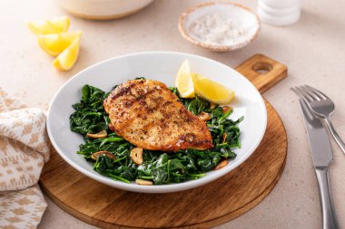 Kızarmış tavuk sotelenmiş ıspanak ve limon, sağlıklı akşam yemeği fikri.