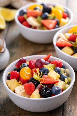 Böğürtlen, narenciye, nane ve bal soslu ahşap bir masada meyve salatası.