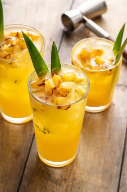 Izgara ananas kokteyli ya da ananas yapraklarıyla süslenmiş uzun bardaklarda mocktail, ferahlatıcı yaz içeceği fikri.