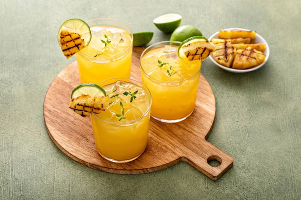 stock image Grilled pineapple margarita garnished with lime wedges and thyme