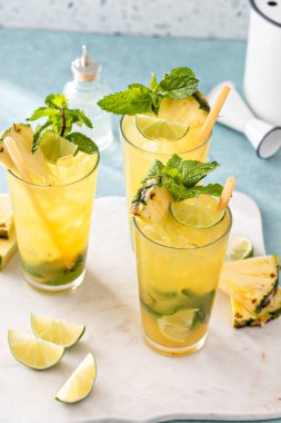 Limonlu ve naneli ananas mojito ve şeker kamışı çubuğuyla süslenmiş bir dilim ananas.