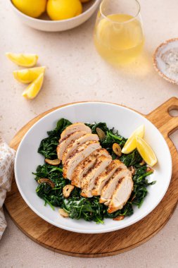 Kızarmış tavuk sotelenmiş ıspanak ve limon, sağlıklı akşam yemeği fikri.