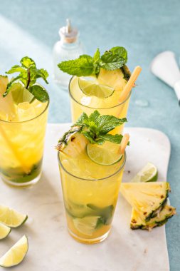 Limonlu ve naneli ananas mojito ve şeker kamışı çubuğuyla süslenmiş bir dilim ananas.