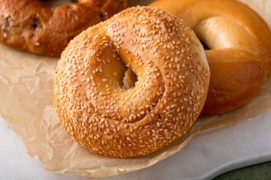 Parşömen kağıdında taze pişmiş simit, tarçınlı kuru üzüm, susamlı ve sade simit.