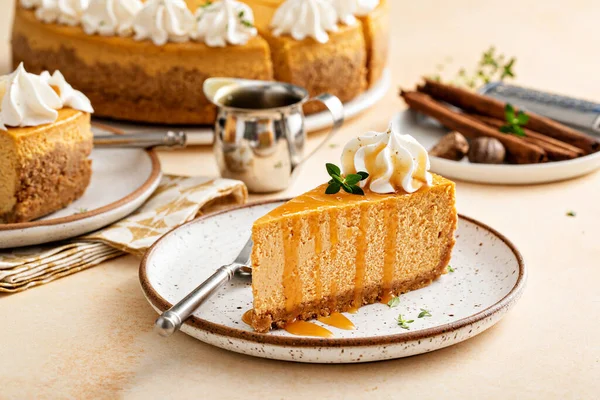 Pumpkin cheesecake with fall spices topped with whipped cream, dessert for Thanksgiving, a slice cut with caramel sauce