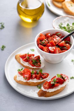 Domates fesleğeni ve krem peynirli bruschetalar ve taze vişneli domates ve otlar.