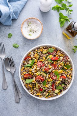 Domatesli sıcak kinoa salatası, mısır ve kabak, taze nane ve bitkilerle birlikte.