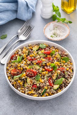 Domatesli sıcak kinoa salatası, mısır ve naneli kabak ve taze otlar.