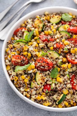 Domatesli sıcak kinoa salatası, mısır ve naneli kabak ve taze otlar.
