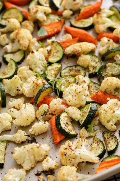 Various vegetables roasted on a sheet pan, cauliflower, zucchini and carrots with herbs, side dish recipe