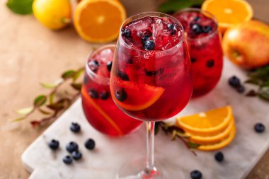 Dilimlenmiş portakal ve yabanmersinli bir sürahide portakal ve böğürtlen sangriası.