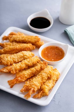 Taze yapılmış ve yemeye hazır soslu bir tabakta pişmiş tempura karidesi.