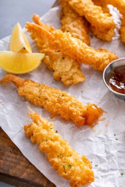 Servis tahtasında taze yapılmış ve yenmeye hazır soslu tempura karidesi pişirdim.