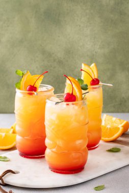 Tiki bardaklı kasırga kokteyli, tropikal, rom bazlı portakal ve kiraz garnitürlü kokteyl.