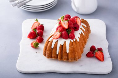 Üzerinde şeker jölesi ve kırmızı böğürtlen olan yarım kilo kek.