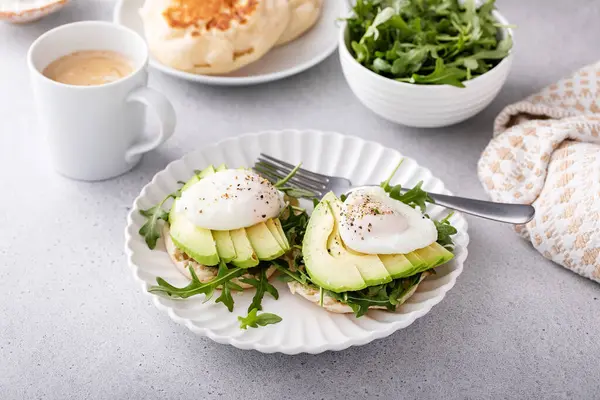 Englische Muffins Mit Rucola Avocado Und Pochierten Eiern Gesunde Eier lizenzfreie Stockbilder