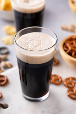 Uzun bardaklarda koyu siyah bira fındıklı, krakerli ve cipsli.