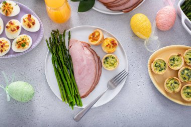 Paskalya brunch masasında jambon iksiri tabağında kuşkonmaz ve mini keklerle birlikte.