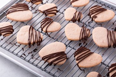 Kalp şeklinde çilek aromalı kurabiyeler, serinletici bir rafta siyah çikolata serpiştirilmiş.