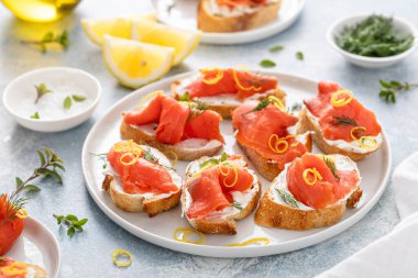 Krem peynirli, dereotlu ve limonlu füme somon crostini servis tabağında.