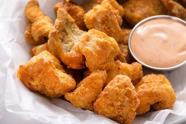Fried catfish nuggets in a bowl with dipping sauce
