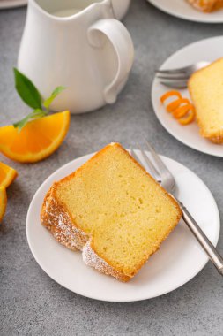 Tabakta portakallı kek dilimi hazır, üzeri pudra şekerli kek.