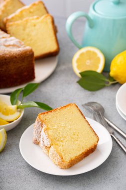 Tavada pişirilmiş limonlu kek üzerine pudra şekeri dilimlenmiş, tabakta dilimlenmiş.