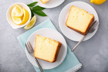 Tavada fırınlanmış limonlu kek üzerine pudra şekeri dilimlenmiş, bir tabakta üç dilim.