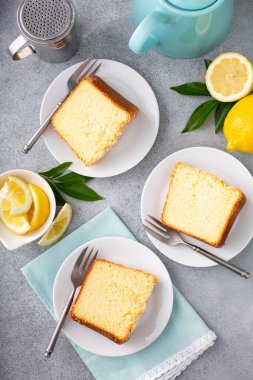 Tavada fırınlanmış limonlu kek üzerine pudra şekeri dilimlenmiş, bir tabakta üç dilim.